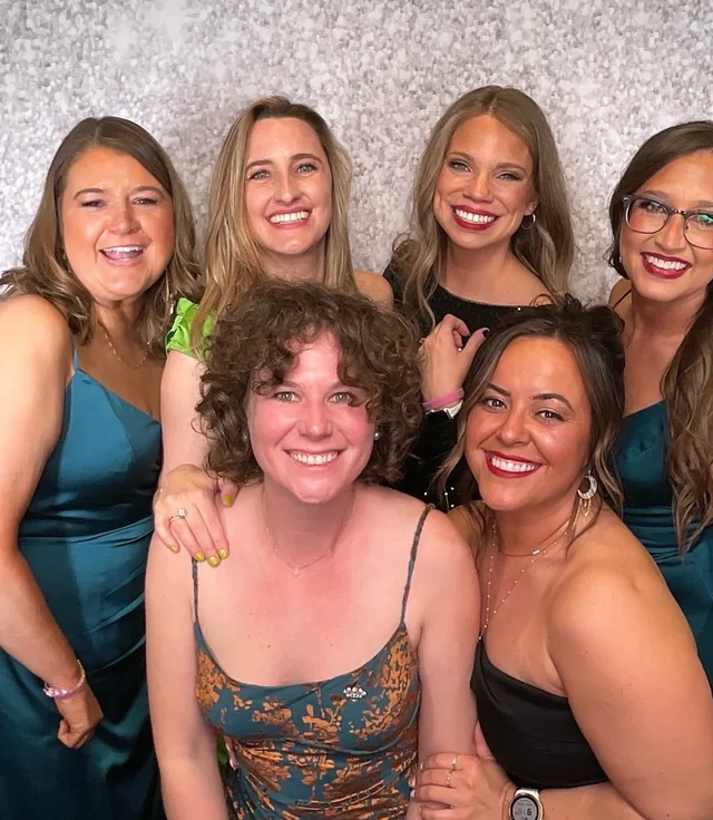Guests in gowns laughing together at the booth during a charity ball