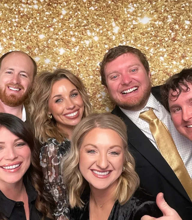 A group of guests packed in front of the gold sequin backdrop