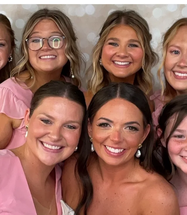 Bridesmaids in pink crowding into the booth together at a wedding
