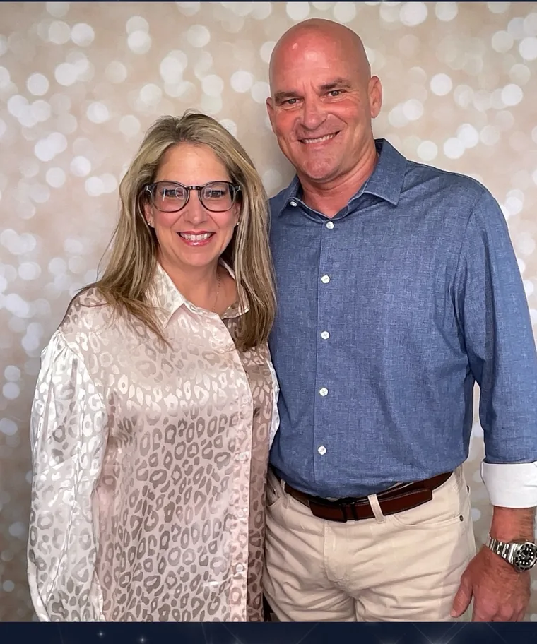 A couple posing at the booth backdrop at a fundraiser evening