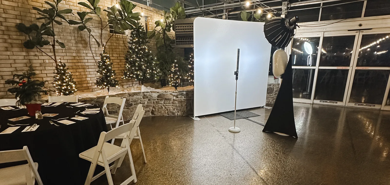 The open-air photo booth and a white backdrop set up in a brick event hall before guests arrive