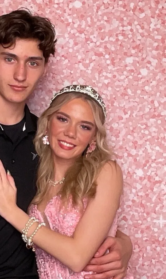 A couple posing together in front of a pink sequin backdrop