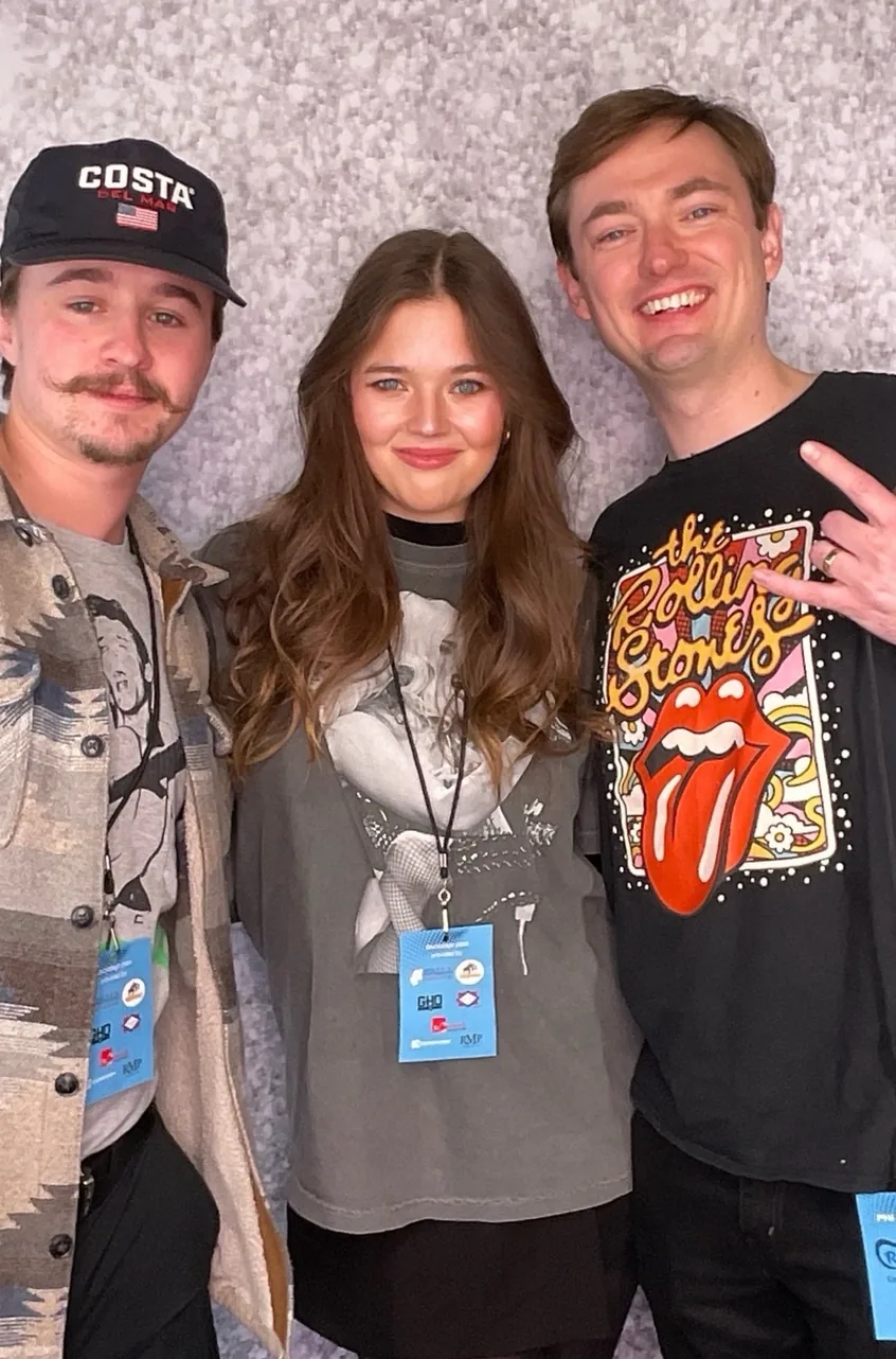 Three friends with arms around each other in front of a silver sequin backdrop