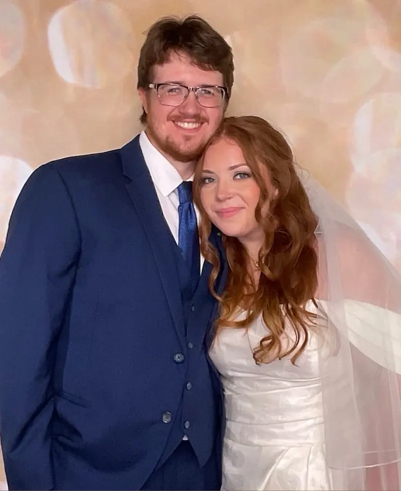 A bride and groom in the photo booth in front of a soft gold backdrop