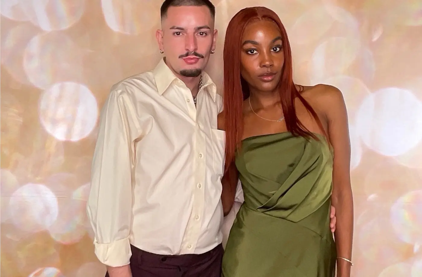 A couple photographed in the booth against a soft gold backdrop