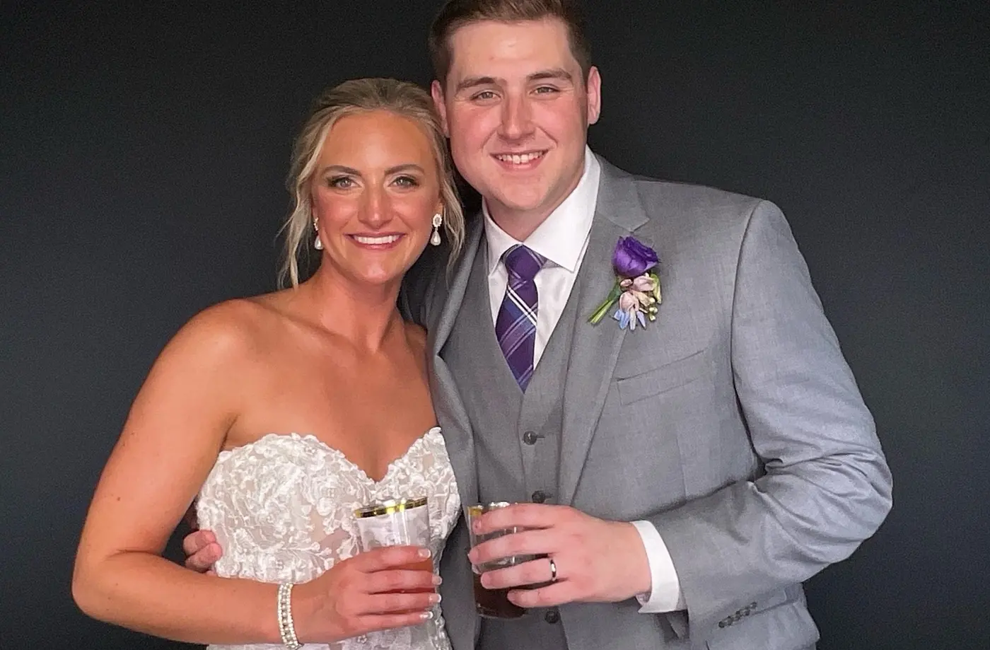 A bride and groom holding drinks in the photo booth