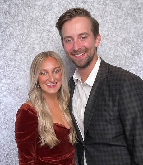 A couple in evening wear posing together in front of a silver sequin backdrop